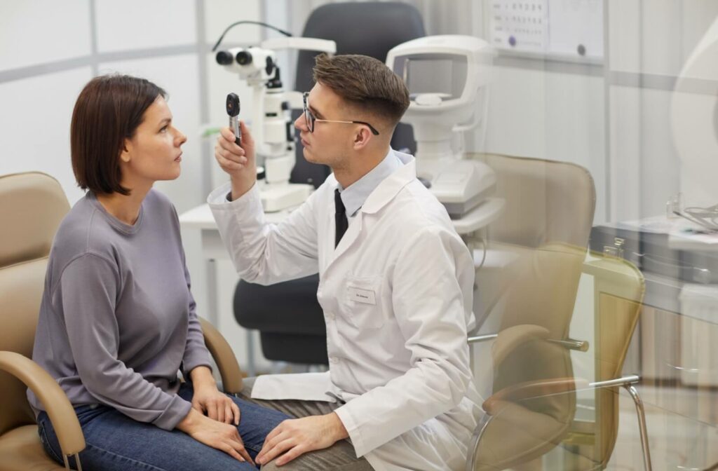 An optometrist uses a retinoscope to examine the patient's eyes during a comprehensive eye exam.