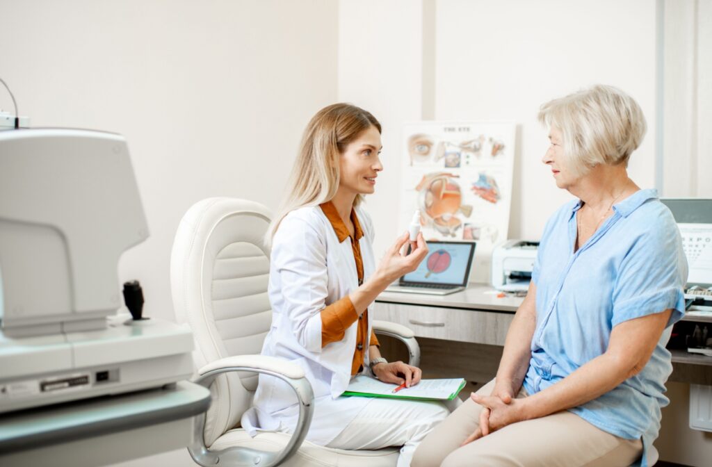 An optometrist discusses dry eye management strategies with a patient while holding a bottle of eye drops.
