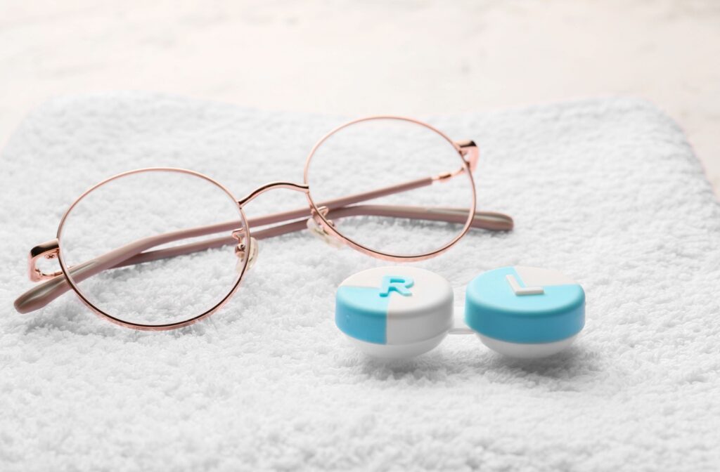 A close up of a pair of thin metal framed glasses next to a blue contact lens case