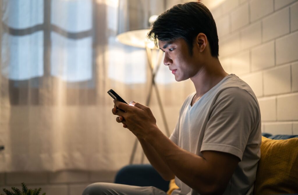 A person looks at their phone in a dimly lit room
