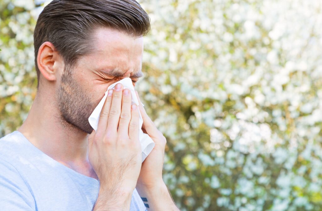 A person blowing their nose into a tissue due to allergies