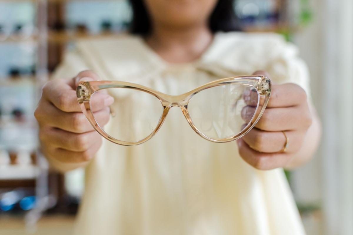 a person holding up a pair of yellow transparent framed glasses